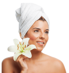 Woman with a towel on her head holding a white lily against a white background  